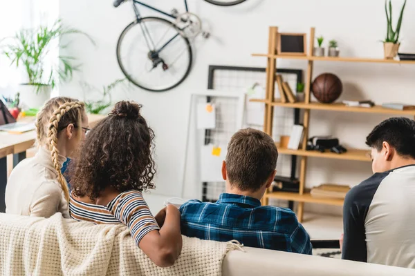 Vue arrière d'amis multiculturels assis sur un canapé — Photo de stock