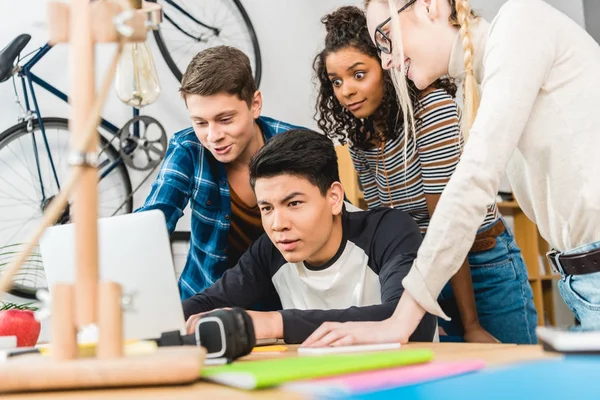 Gruppo di adolescenti multiculturali utilizzando il computer portatile a tavola — Foto stock