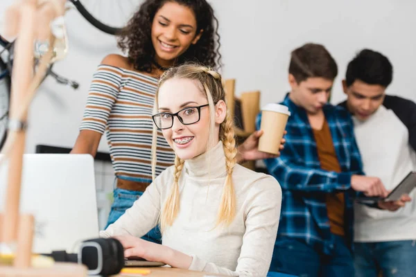 Ragazza con l'apparecchio acustico seduto con il computer portatile e guardando la fotocamera — Foto stock