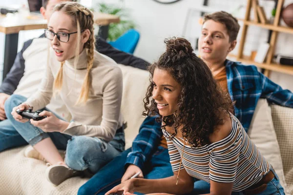 Smiling teenage multiethnic girls playing video game — Stock Photo