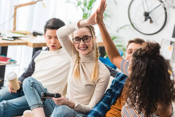 Filles donnant haute cinq pour gagner les garçons dans le jeu vidéo — Photo de stock