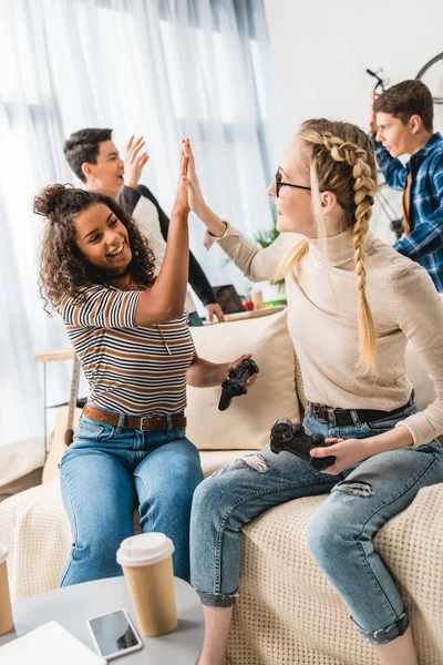 Ragazze multietniche dando il cinque per vincere i ragazzi nel videogioco — Foto stock