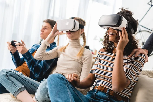 Muchachas adolescentes multiétnicas viendo algo con auriculares de realidad virtual - foto de stock