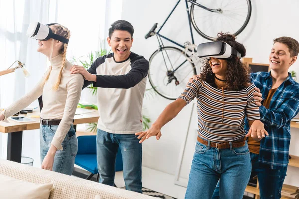 Смеющиеся мальчики с мультикультурными девочками смотрят что-то в наушниках виртуальной реальности — стоковое фото
