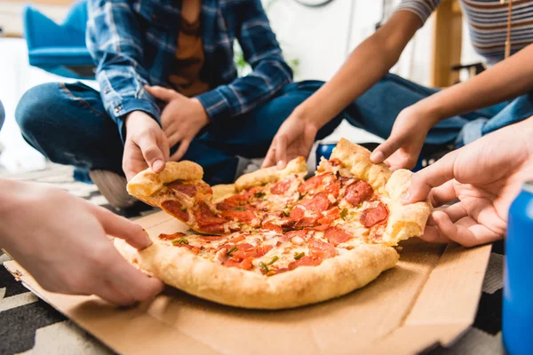 Cropped image of friends taking pizza pieces — Stock Photo