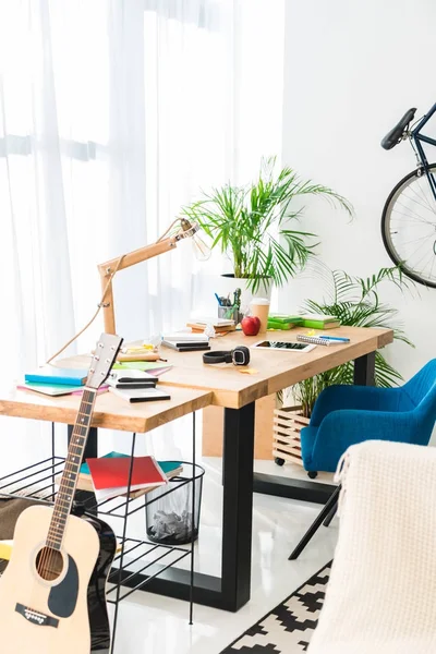 Working table and acoustic guitar at home — Stock Photo