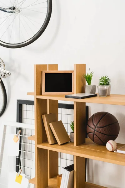 Fahrrad an der Wand und Basket- und Baseballbälle im Regal — Stockfoto