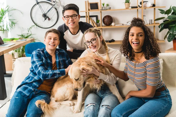 Happy multiethnic teenagers posing with dog — Stock Photo