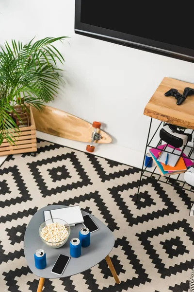 Vista aérea de la mesa con teléfonos inteligentes y palomitas de maíz en la habitación - foto de stock