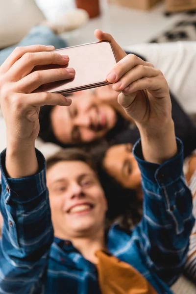 Overhead view of happy teens taking selfie while lying on bed — Stock Photo