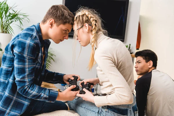 Boy and girl aggressively touching with foreheads while playing video game — Stock Photo