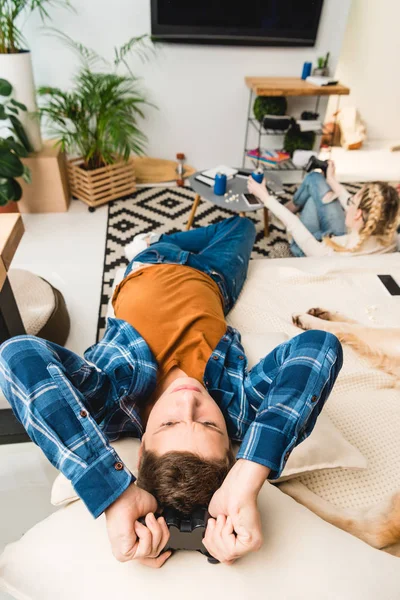 Vue aérienne du garçon bouleversé couché sur le canapé avec un tapis de jeu — Photo de stock