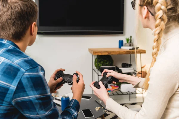 Vista posterior de los adolescentes femeninos y masculinos jugando videojuego - foto de stock