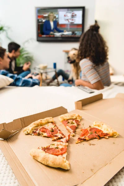 Freunde schauen Nachrichten mit Pizza im Vordergrund — Stockfoto