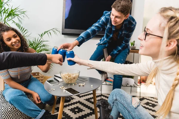 Grupo de adolescentes multiculturales tintineo con latas - foto de stock