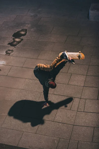 Vista de ángulo alto de skateboarder realizar truco y de pie por una mano - foto de stock