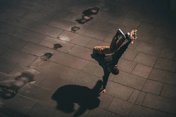 Високий кут зору професійного скейтбордиста, який виконує трюк і стоїть на одній руці — стокове фото