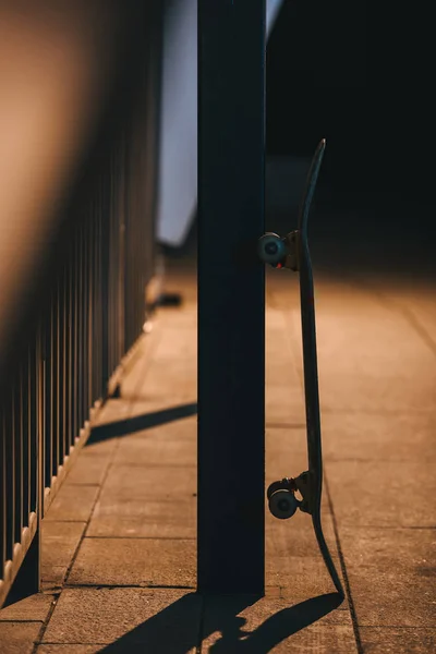 Skateboard leaning on pole at late night — Stock Photo