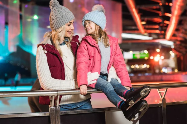 Beautiful happy mother and daughter smiling each other on skating rink — Stock Photo