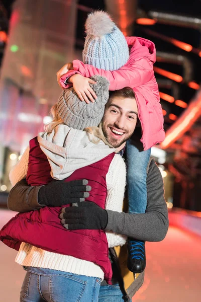 Felice giovane famiglia abbracciare e divertirsi insieme sulla pista di pattinaggio — Foto stock