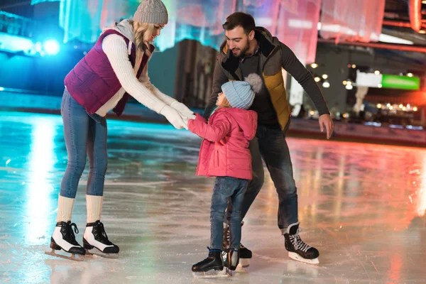 Happy parents teaching adorable little daughter skating on rink — Stock Photo
