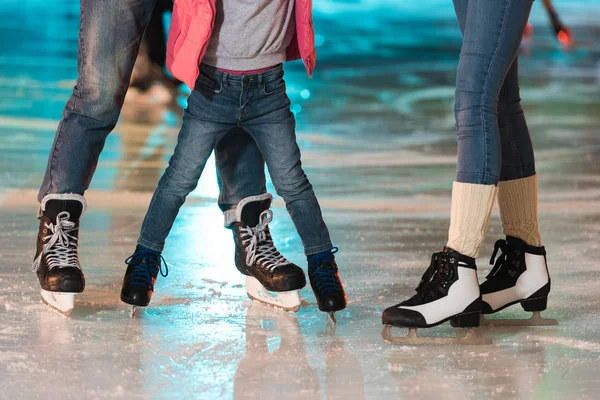 Recortado tiro de la familia joven en patines patinaje juntos en la pista de patinaje - foto de stock