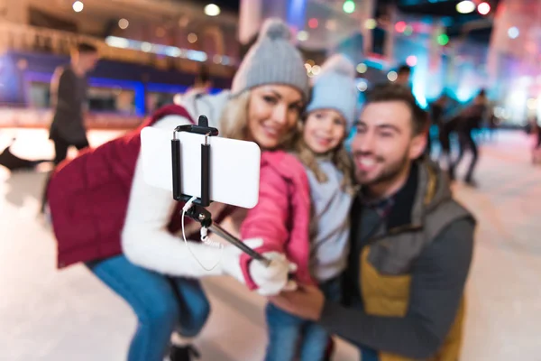 Focalizzazione selettiva della giovane famiglia felice scattare selfie con smartphone sulla pista di pattinaggio — Foto stock