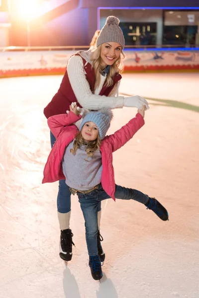 Beau père heureux et fille souriant à la caméra tout en patinant sur la patinoire — Photo de stock