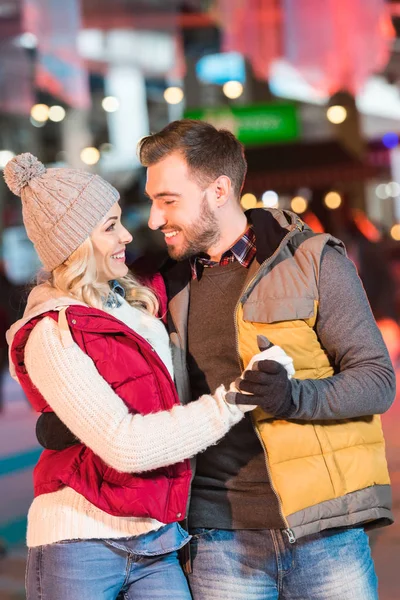 Hermosa pareja joven en el amor de la mano y sonriendo el uno al otro en la pista - foto de stock