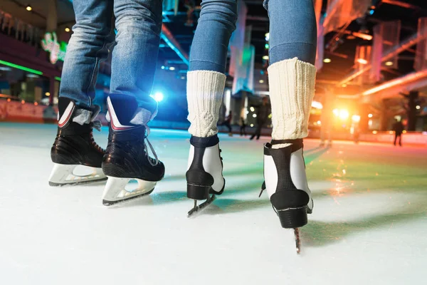 Low section of couple in skates ice skating on rink — Stock Photo