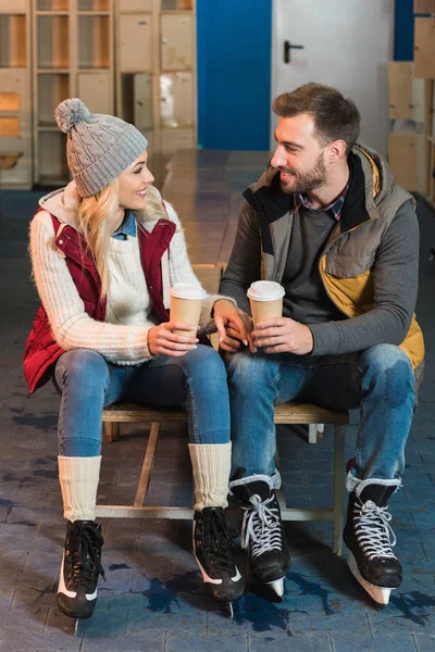Beau jeune couple avec café pour aller sourire sur la patinoire — Photo de stock