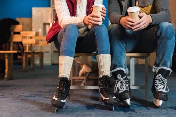 Recortado disparo de joven pareja en patines sosteniendo café para ir en vasos de papel - foto de stock