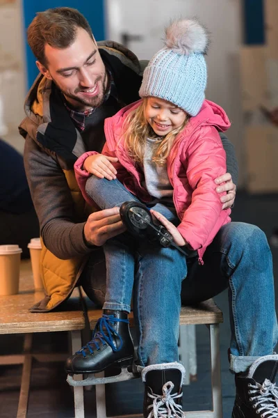 Happy father and daughter wearing skates before ice skating — Stock Photo