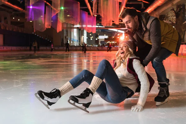 Belo jovem casal ensinando patinação no gelo na pista — Fotografia de Stock