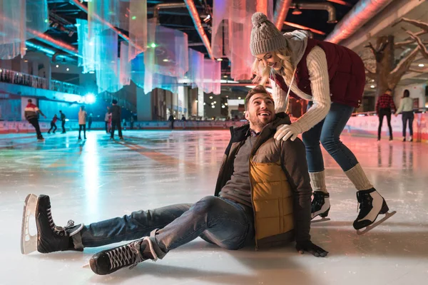Hermosa sonrisa joven pareja enseñando patinaje sobre hielo en pista de patinaje - foto de stock