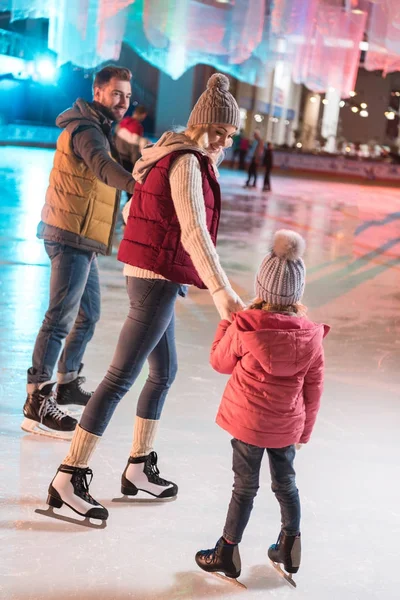 Belle jeune famille heureuse tenant la main sur la patinoire — Photo de stock