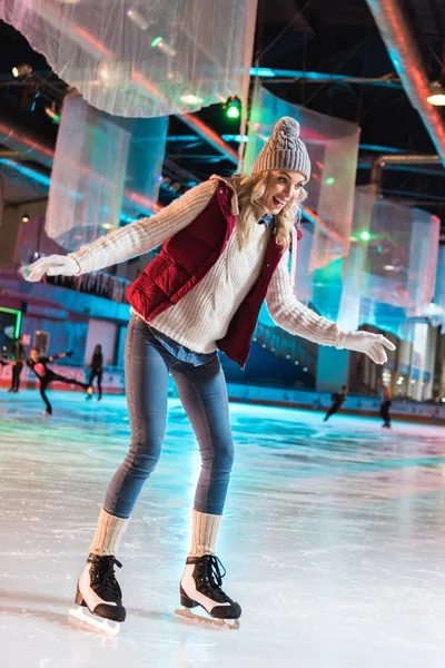 Animado bela jovem patinação no gelo na pista — Fotografia de Stock