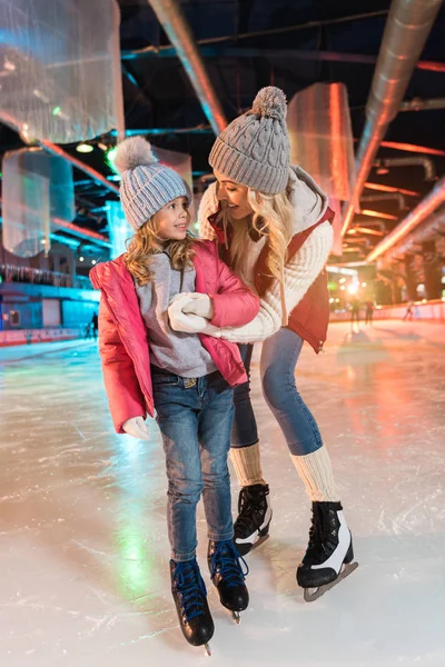 Щаслива мати і дочка тримаються за руки і посміхаються один одному на ковзанах — стокове фото