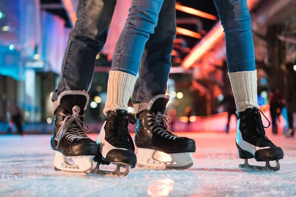 Close-up partial view of young couple in skates ice skating on rink — Stock Photo