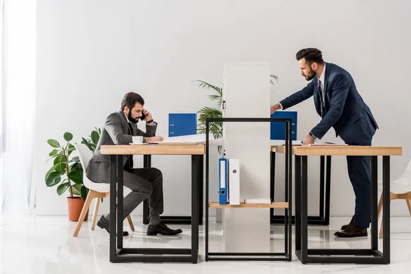 Vue de côté des hommes d'affaires travaillant aux tables dans le bureau — Photo de stock