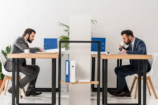 Vista lateral de los empresarios que trabajan y beben café en el lugar de trabajo - foto de stock