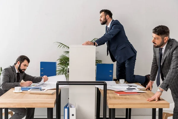 Collègues espionnage sur homme d'affaires au-dessus de partition dans le bureau — Photo de stock