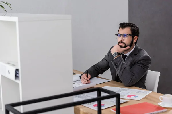 Nachdenklicher Geschäftsmann sitzt am Tisch und blickt auf — Stockfoto