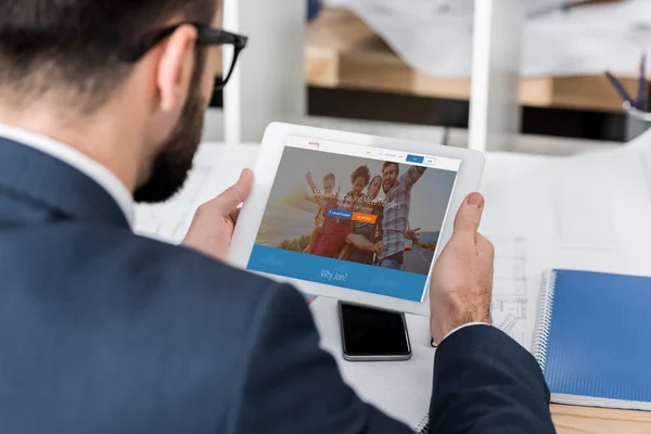 Hombre de negocios celebración de tableta con página de couchsurfing cargado - foto de stock