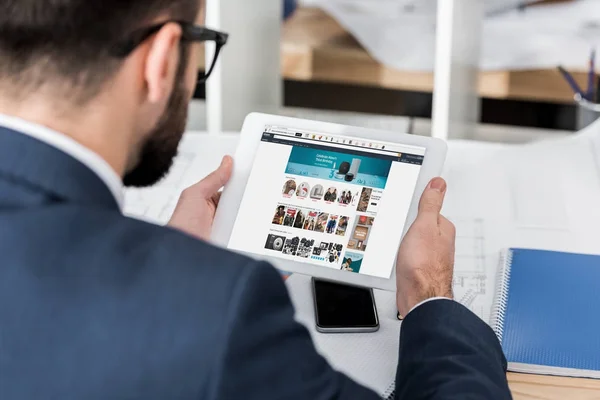 Geschäftsmann hält Tablet mit geladener Amazon-Seite — Stockfoto