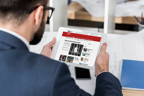 Businessman holding tablet with loaded bbc news page — Stock Photo