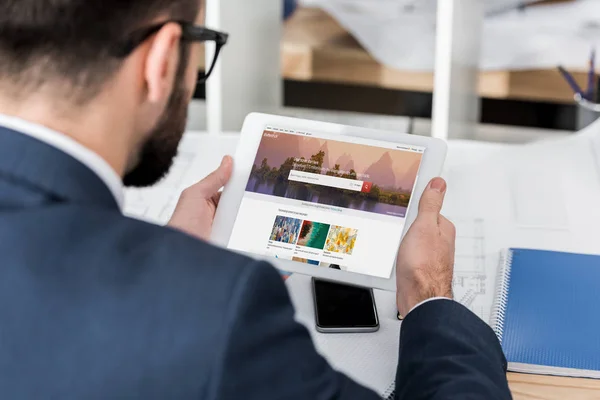 Businessman holding tablet with loaded shutterstock page — Stock Photo