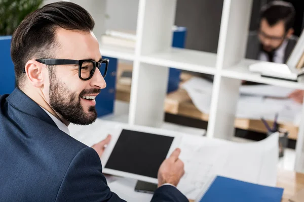 Homem de negócios sorrindo segurando tablet na mesa de trabalho — Fotografia de Stock