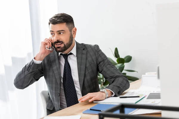 Homme d'affaires souriant parlant par smartphone dans le bureau — Photo de stock