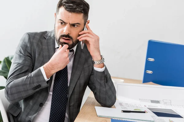 Pensativo hombre de negocios hablando por teléfono inteligente en la oficina - foto de stock